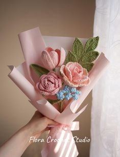 a hand holding a bouquet of crocheted flowers