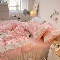 a bed with pink and white checkered comforter on top of it next to a window