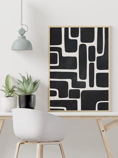 a black and white art print on a wall next to a table with a plant