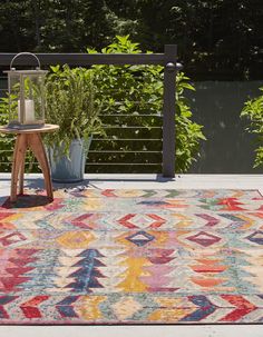 a multicolored area rug with a wooden stand and potted plants in the background