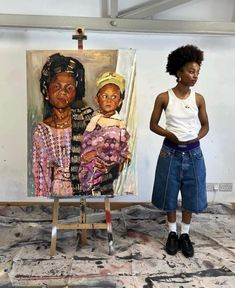 a woman standing in front of a painting on an easel next to another woman