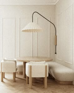 a table with chairs and a lamp in a room that has white walls, wood floors and wooden flooring