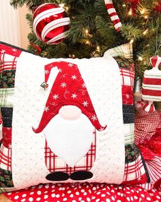 a christmas pillow with a santa clause on it next to a christmas tree and ornaments