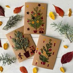 three cards with christmas trees on them surrounded by autumn leaves and other things to make it look like they are made out of cardboard