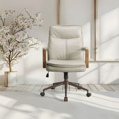 a white office chair sitting in front of a vase with flowers on the side and a window behind it