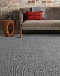 a living room with grey carpet and brick wall