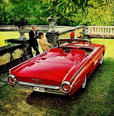 a man and woman standing next to a red car