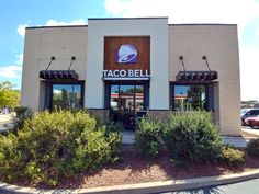 a taco bell restaurant is shown in front of some bushes and shrubs on the side of the building