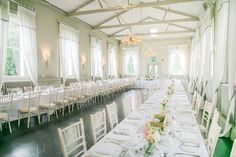 a long table is set up with white linens and place settings for an event