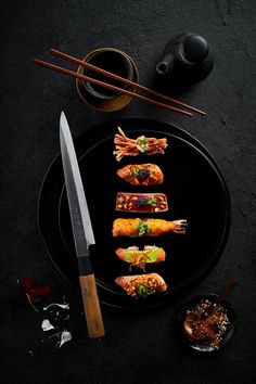 a black plate topped with sushi and chopsticks