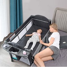 a woman laying on top of a bed next to a baby in a crib