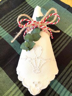 a white napkin with some green leaves and red and white striped twine on it