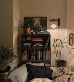 a bedroom with a bed, bookshelf and plants