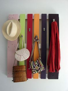 a colorful wall hanging with hats, purses and scarves on it's hooks