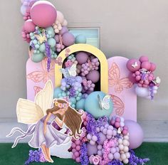 a fairy themed birthday cake with balloons and flowers on it's side, surrounded by decorations