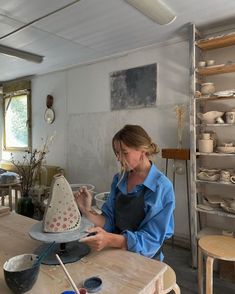 a woman is working on a cake in a studio with bowls and other items around her