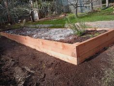 a wooden garden bed with plants growing out of the top and dirt on the bottom