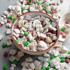 a bowl filled with white and green candy mix next to a spoon on a table