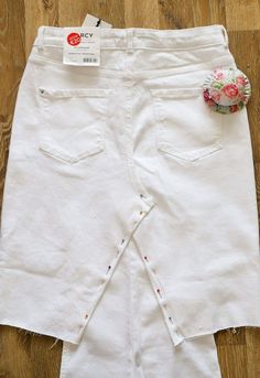 a pair of white jeans with flowers in the pocket