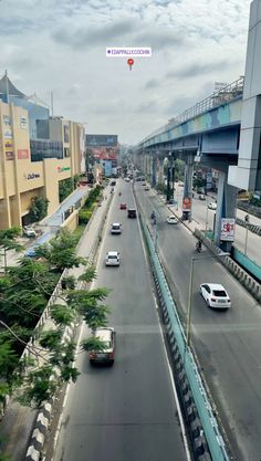 cars driving down an empty city street with tall buildings on either side and overpasss above