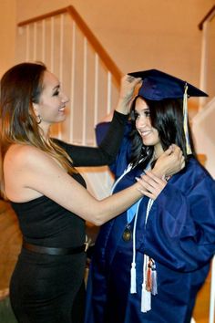 two women in graduation gowns and one is adjusting the cap on another woman's head