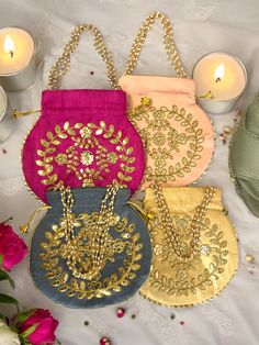 three purses with chains on them sitting next to candles