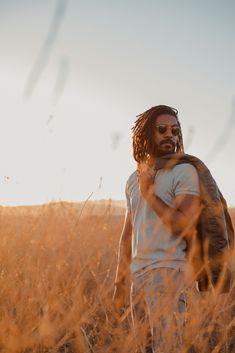 a man with dreadlocks walking through tall grass