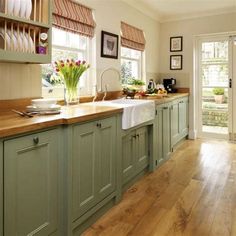 a kitchen filled with lots of green cabinets and counter top space next to a wooden floor