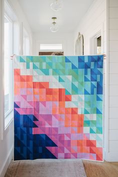 a colorful quilt hanging on the wall in a hallway