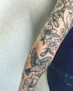 a woman with a bird and flowers tattoo on her arm