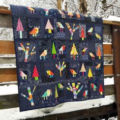 a quilt hanging on a fence in the snow