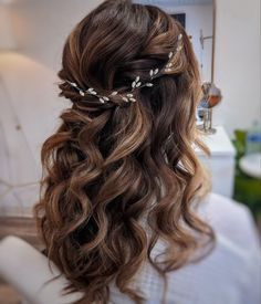 the back of a woman's head with long wavy hair and a flower in her hair