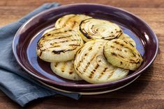 grilled onions on a purple plate with a blue napkin and wooden table top in the background