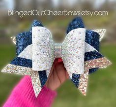 follow us on tiktok @blingedoutcheerbows to see brand new bow styles first!This listing is for 1 rhinestone white, gold , and navy cheer bow ready to ship.  Custom team orders are available for 10+ bows.  You can customize up to 3 colors for the triple threat bow.  Rhinestone cheer bow I've made triple threat bows for local, state, regional and national championships.  Please allow 4 weeks for customization. like us on facebook "blinged out cheer bows" Bow Styles, Competition Cheer, Competitive Cheer, Cheer Bow, Cheer Bows, Triple Threat, Navy And White, Mother’s Day, Beauty Book