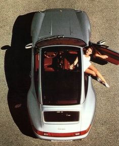 a woman sitting in the back of a silver sports car