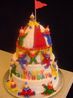 a birthday cake with clowns on it and a flag sticking out of the top