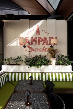 an outdoor seating area with green and white striped benches, potted plants and a sign that says impact soda