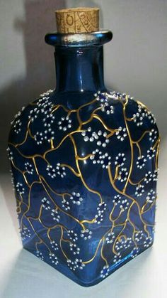 a blue glass vase with gold and white designs on the top is sitting on a table