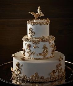 a three tiered white wedding cake with gold decorations