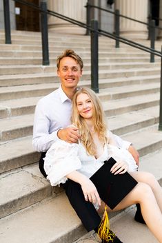 a man and woman are sitting on the steps together, posing for a photo with their arms around each other