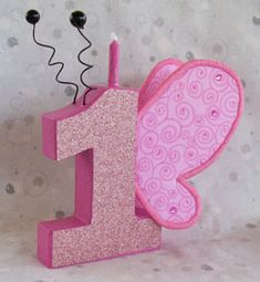 a pink number one shaped like a butterfly with a candle in it's mouth