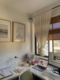 a desk with a laptop computer sitting on top of it next to two framed pictures