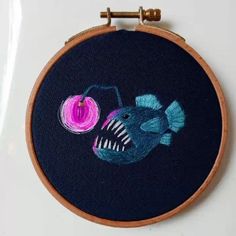 an embroidered fish with a spool of yarn on it's back is shown