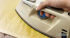 a person is using an iron on a yellow blanket