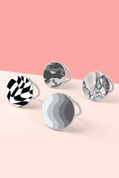 four rings with different designs on them sitting on a table next to a pink wall