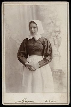 an old black and white photo of a woman in a dress with a bonnet on her head