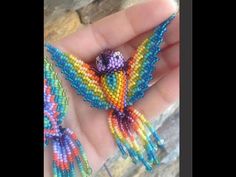 a hand holding two colorful beaded birds on it's palm, one is multicolored and the other is blue