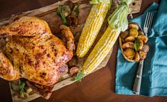 grilled chicken, potatoes and corn on the cob with a blue napkin next to it