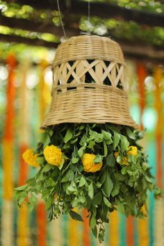 a wicker basket hanging from the ceiling with yellow flowers in front of colorful ribbons