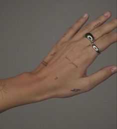 a person's hand with tattoos on it holding something in the air to their left